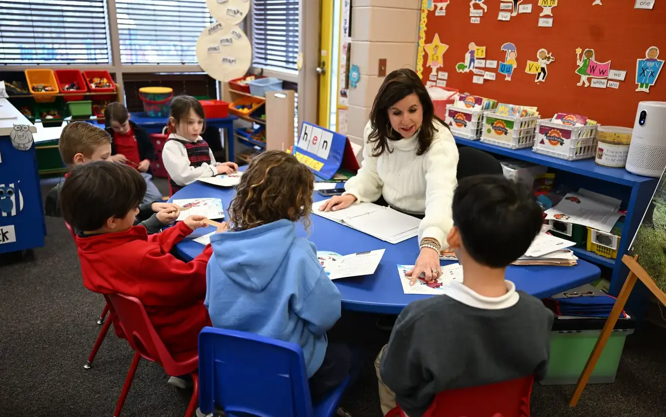 lower school teacher sitting with kids at table
