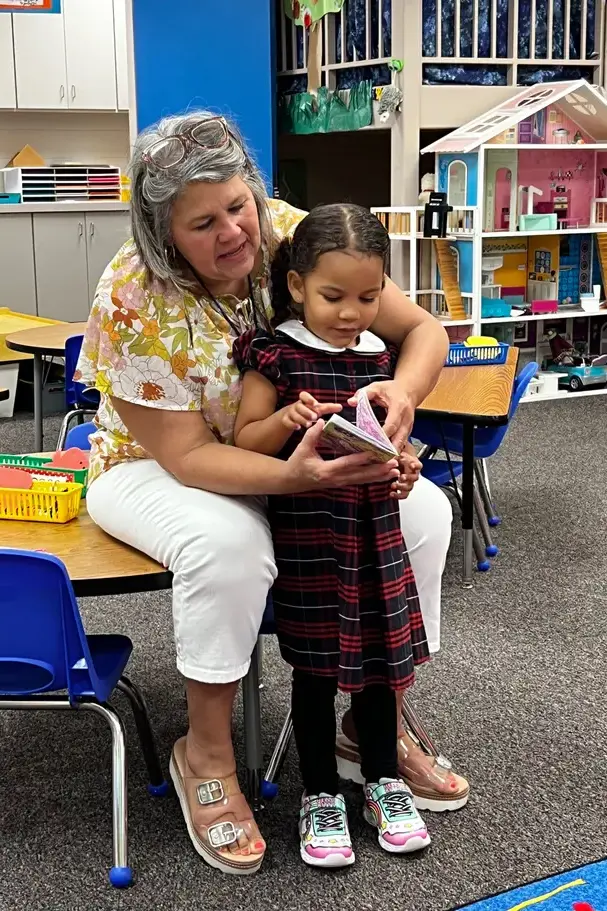 teacher reading with preschool girlon page image