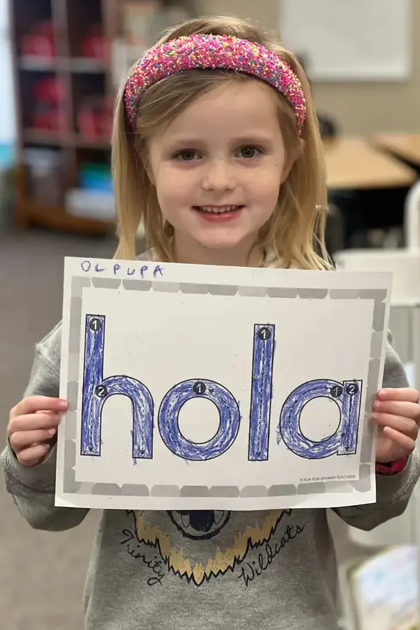 preschool girl at spanish class holding sign saying holaon page image