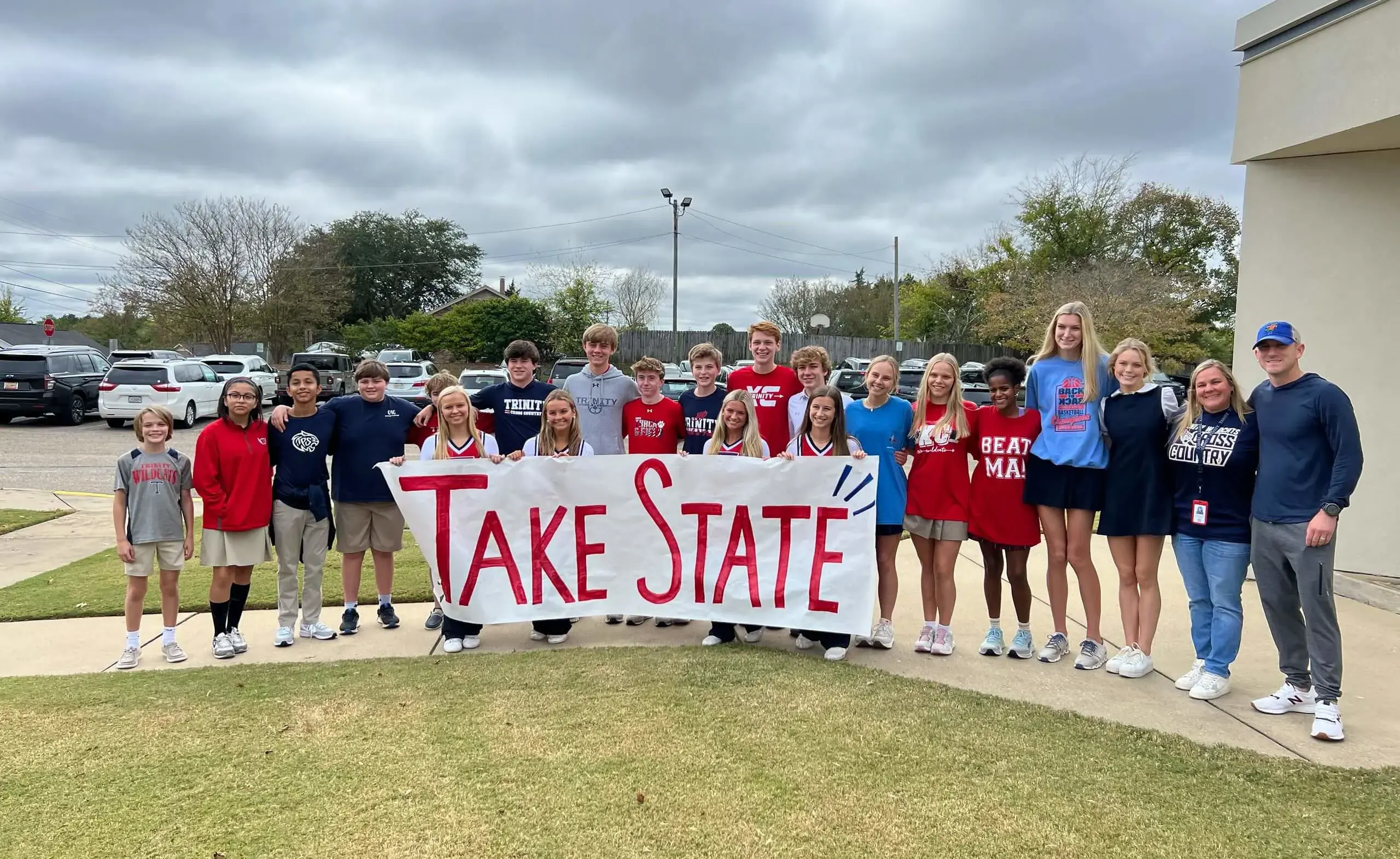 Cross country students holding a banner reading 'TAKE STATE'